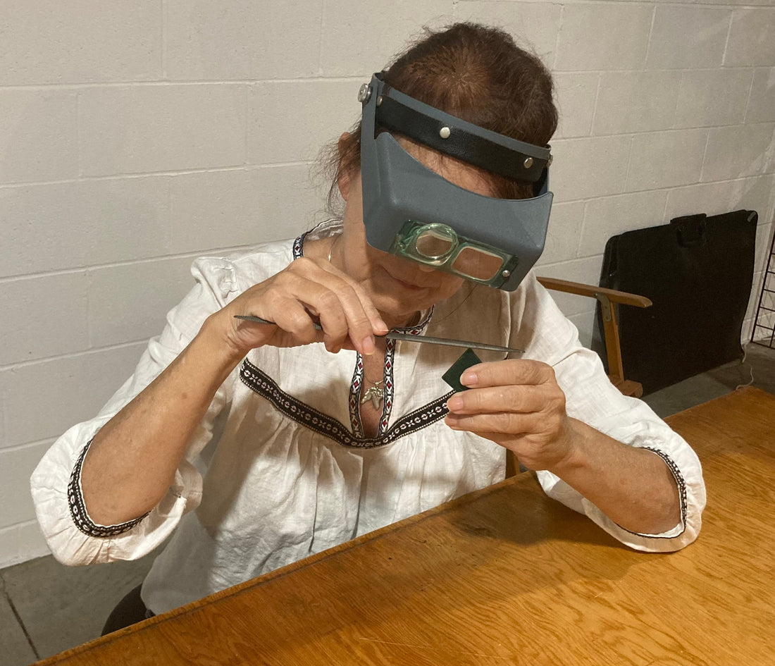 Salina Ramsay carving a horse-inspired jewelry design in wax at her studio bench, illustrating the journey from canvas to gold.