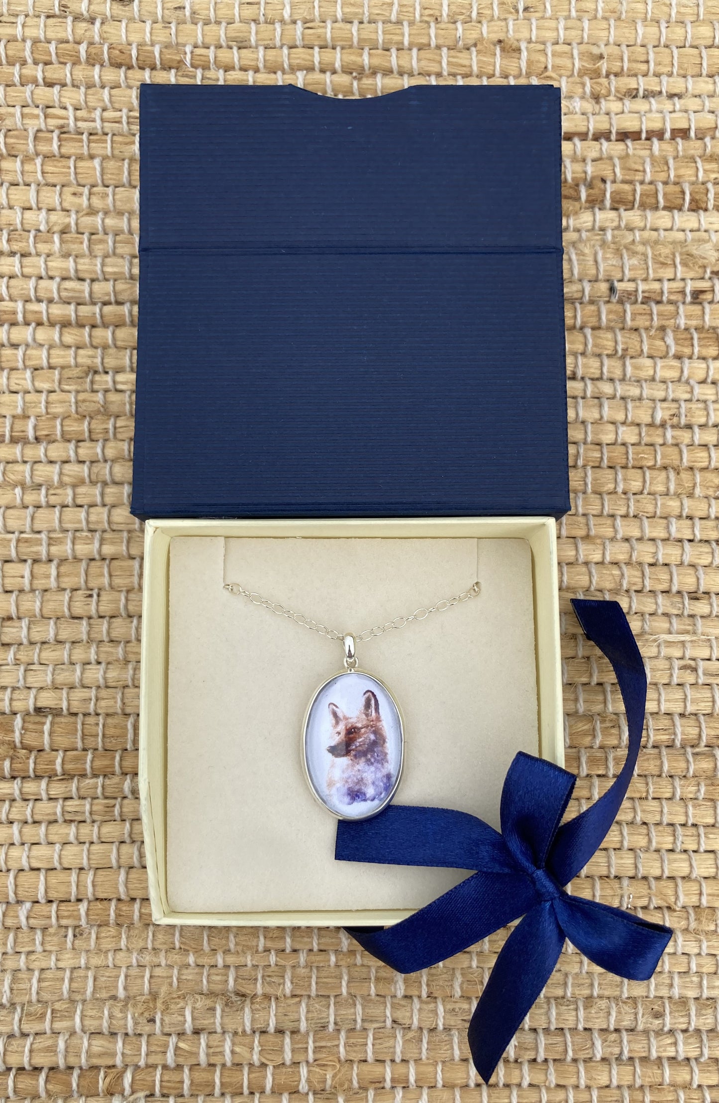Sterling silver fox pendant featuring a reproduction of an original watercolor by Salina Ramsay beneath a crystal-clear dome. The artwork captures the alert expression and natural beauty of a fox in soft woodland tones, creating a collectible wearable work of art inspired by nature and country life.