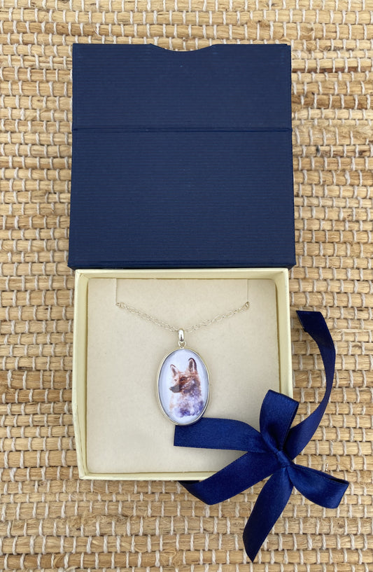 Sterling silver fox pendant featuring a reproduction of an original watercolor by Salina Ramsay beneath a crystal-clear dome. The artwork captures the alert expression and natural beauty of a fox in soft woodland tones, creating a collectible wearable work of art inspired by nature and country life.